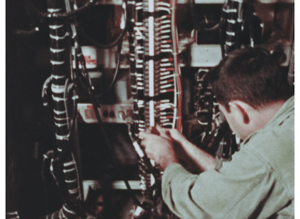 Technician attaches many red and green and black wires to a connection terminal of some kind.