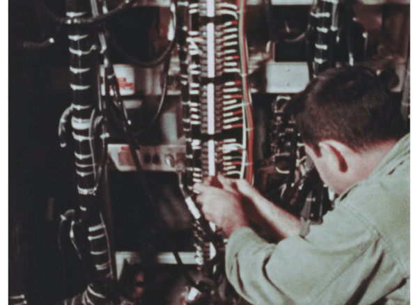 Technician attaches many red and green and black wires to a connection terminal of some kind.