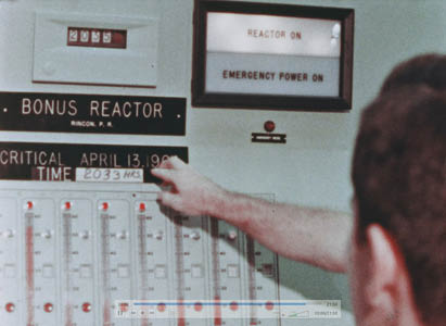 Control room view showing placard about BONUS going critical on April 13, 1964 at 2033 hours. the REACTOR ON sign is lit.