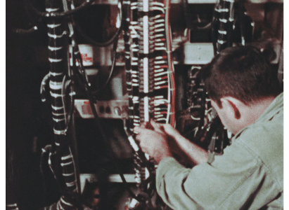 Technician attaches many red and green and black wires to a connection terminal of some kind.