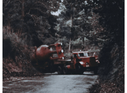 Truck carrying BONUS vessel gets stuck in a tight forested corner on the street. It is basically pinned as it tries to round the corner.
