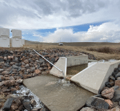 A concrete ramp leads to a water source, with a truck parked nearby. AI generated content