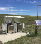Two white appliances are sitting on a concrete slab in a grassy field. AI generated content